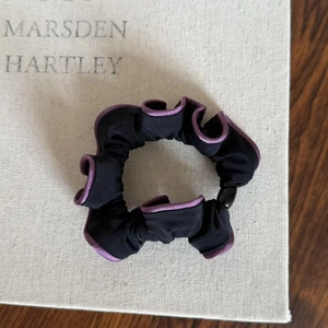 Detail of Korean style scrunchie with purple contrast edging and sleek satin texture