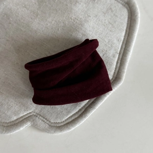 Macro shot of deep burgundy high-elastic velvet hair scrunchie on a textured beige mat