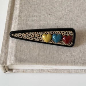 Triangle leopard print hair clip with colorful 3D hearts on a natural linen background
