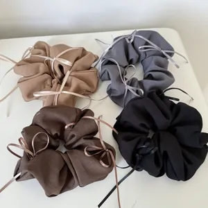 Close-up of fabric scrunchies in khaki, grey, brown, and black with ribbon bows
