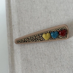 Detail of leopard print triangle hair clip with red, blue and yellow 3D hearts