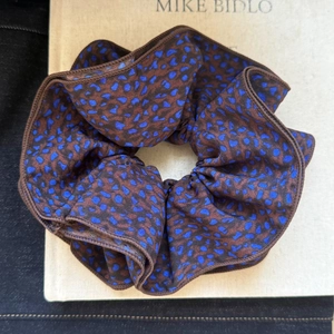 Detailed view of large leopard print scrunchie featuring blue and brown chiffon fabric