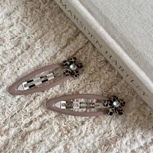 Paire de barrettes à fleurs léopard élégantes avec strass sur tissu beige doux