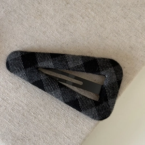 Detail einer Vintage-Haarklammer mit grau-schwarzem Karomuster auf strukturiertem Stoff