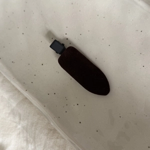Détail macro de la barrette à cheveux en velours marron foncé sur un plateau en céramique
