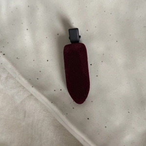 Détail d'une barrette à cheveux en velours rouge foncé avec une structure classique sur pierre