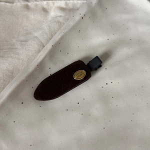 Détail de la pince à cheveux en velours marron foncé avec boucle dorée Smile Happy