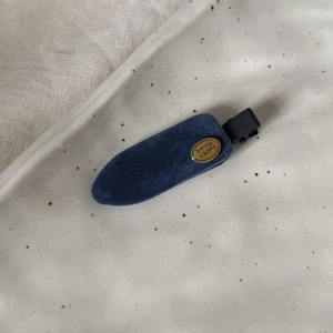 Détail macro d'une barrette en velours bleu foncé avec décoration Smile Happy dorée