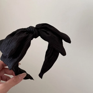Close-up of a wide black pleated bow headband with a textured fabric finish and stylish design