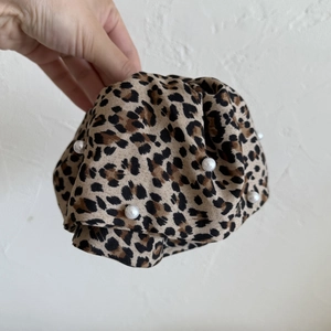 Detailed close-up of a leopard print scrunchie decorated with elegant white faux pearls