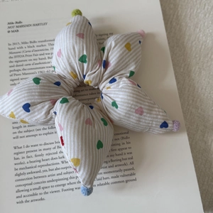 Close-up of heart-patterned striped scrunchie with colorful pom-poms on a book