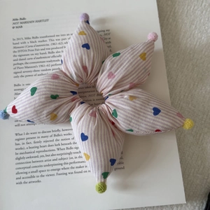 Detailed shot of striped star hair scrunchie with colorful heart print and small pompoms