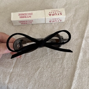 Detail of elegant black velvet bow hair clip on a soft textured linen background