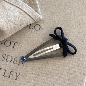 Korean style navy bow hair clip with blue crystal detail on a beige linen background