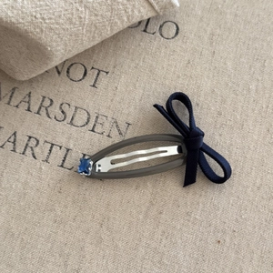 Detailed view of sweet blue bow hair clip with gray resin coating and blue gemstone