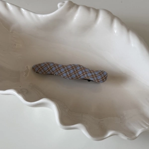 Gros plan sur une pince à cheveux rétro à carreaux bleus sur un plateau décoratif blanc