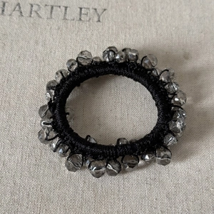 Macro view of a black elastic hair tie with faceted gray crystal beads on linen fabric