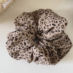 Close-up of leopard print hair scrunchie showing soft fabric texture and pleated design