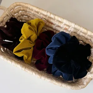 Five-piece set of solid color milk velvet scrunchies in autumn tones inside a woven basket