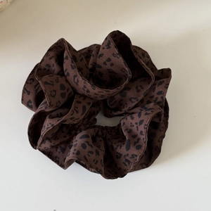 Detailed close-up of dark brown leopard print scrunchie with layered fabric texture