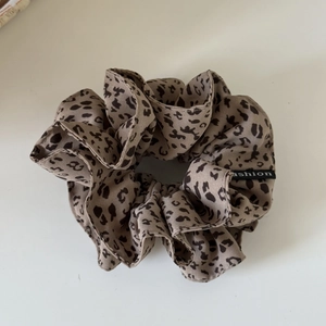 Macro detail of leopard print hair scrunchie with fashion label on white background