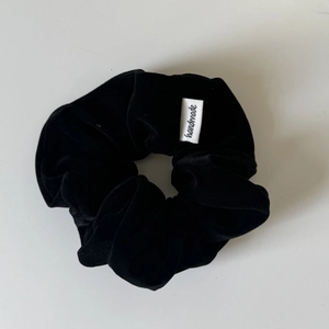 Detail of black velvet scrunchie with a handmade white woven label for hair styling