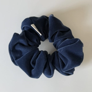 Detail of navy blue velvet scrunchie showing fabric texture and woven brand label