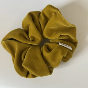 Detailed view of mustard yellow velvet scrunchie showing soft texture and quality stitching