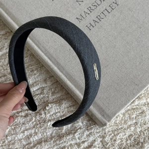 Close-up of dark grey striped fabric headband with silver metal logo on book