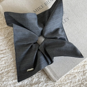 Detail of grey striped fabric scrunchie with a gold Hand Made metallic tag detail