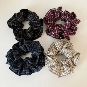 Detail of four plaid hair scrunchies in gray, red, blue, and beige with handmade label