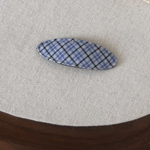 Vintage blue and black plaid fabric oval hair clip on light beige linen background