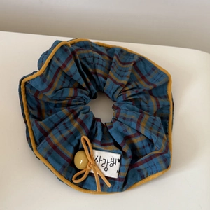 Blue and red plaid fabric scrunchie with yellow trim and small bow hair accessory