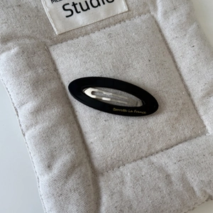Détail d'une barrette ovale noire en acétate avec gravure dorée Barrette La France