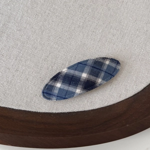 Macro detail of blue and white checkered plaid fabric texture on an oval BB hair clip