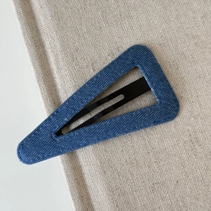 Macro shot of blue denim fabric texture on a triangular BB hair clip for women