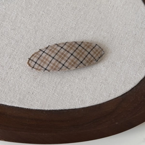 Macro shot of vintage plaid fabric hair clip in earth tones on a rustic wooden background