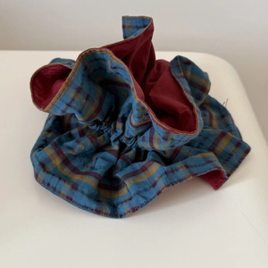 Detailed close-up of a large red, blue, and yellow plaid fabric scrunchie with soft pleats
