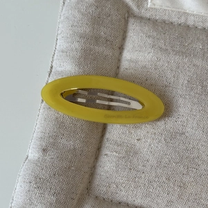 Détail d'une barrette ovale en acétate jaune avec l'inscription Barrette La France