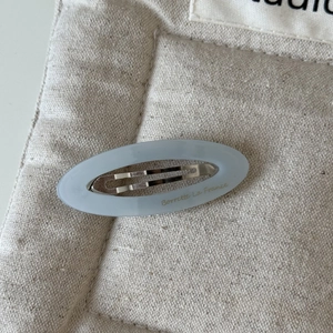 Détail d'une barrette ovale en acétate bleu clair gravée Barrette La France