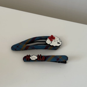 Detail of red and blue plaid fabric hair clips featuring a cartoon dog and Hello text