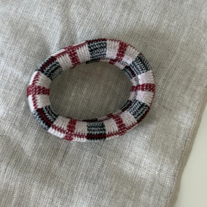 Close-up of elastic striped hair scrunchies in red and navy knit fabric on grey background