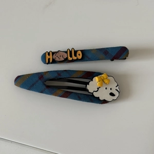 Detail view of blue plaid hair clips featuring cute cartoon dogs and Hello label tags