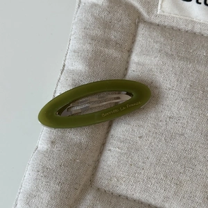 Détail de la barrette ovale en acétate vert olive avec inscription dorée élégante