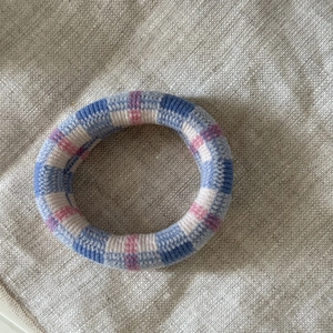 Detailed macro shot showing the striped knit texture and soft blue-pink fabric of the hair tie