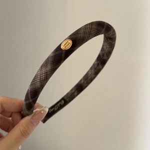 Detailed view of vintage plaid headband with golden SMILE HAPPY metal emblem and anti-slip lining