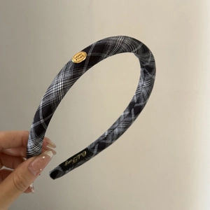 Detail of checkered headband with golden oval Smile Happy metal plaque and soft fabric