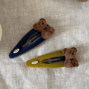 Cute flocked bear hair clips in navy blue and yellow with Love metal tags on linen fabric