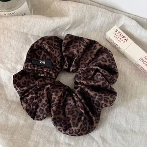 Elegant leopard print satin scrunchie for hair styling on soft linen with accessories
