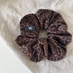 Classic leopard print scrunchie in satin silk with luxury branded label on grey fabric